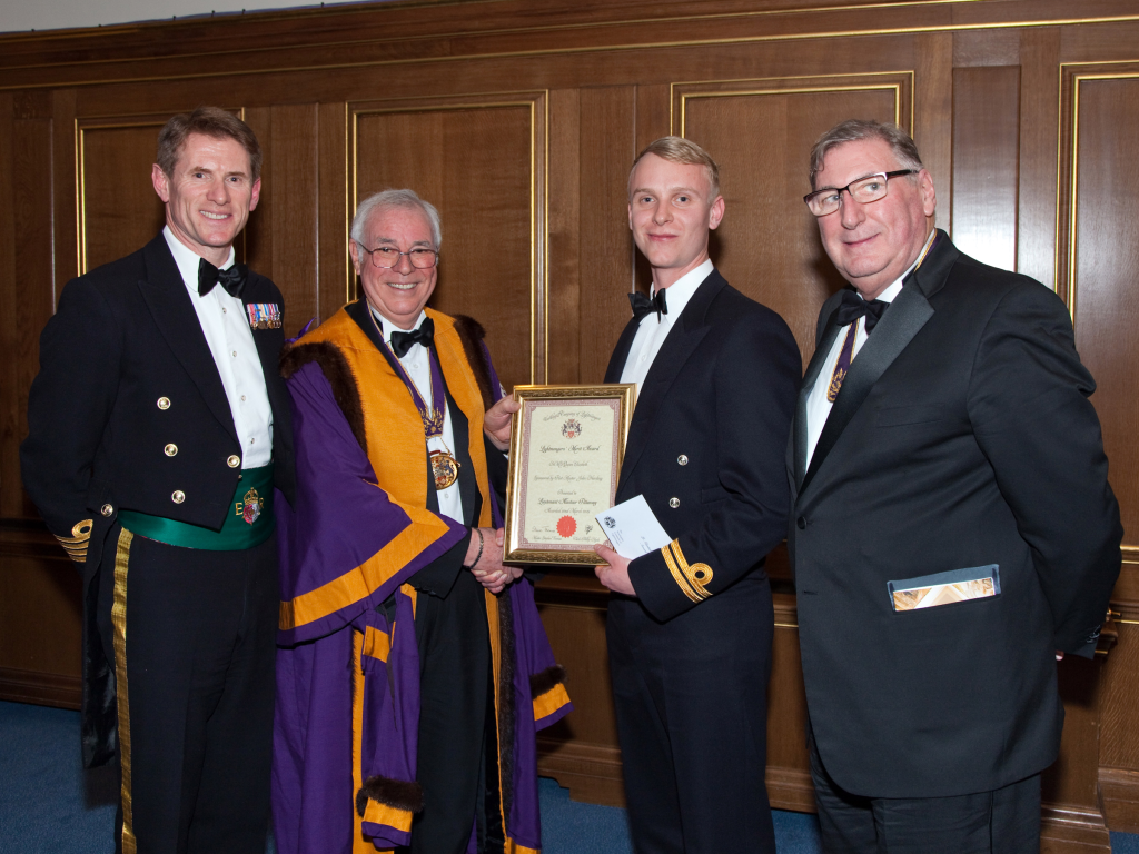 Sub-Lieutenant Alistair Pittaway of HMS Queen Elizabeth, receiving his Award from the Master and Sponsor, Past Master John Harding, together with Captain Nick Cooke-Priest